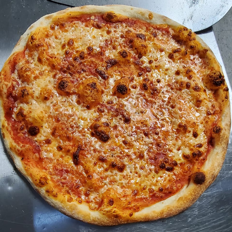 A freshly baked Eastside Market cheese pizza with a golden crust and bubbly, melted cheese.